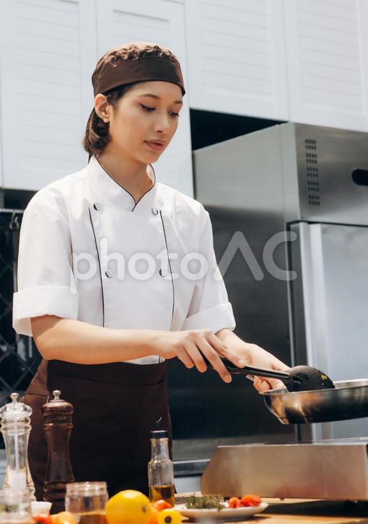 フライパンで調理スプーンで炒めている女性シェフ キュイジーヌ,キッチン,厨房の写真素材