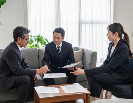 応接室でお客様に資料を説明する上司と部下の写真
