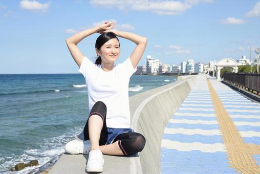 海岸でストレッチをする女性 海岸でストレッチをする女性の写真