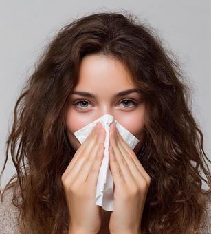ティッシュで鼻をかむ女性のクローズアップの写真