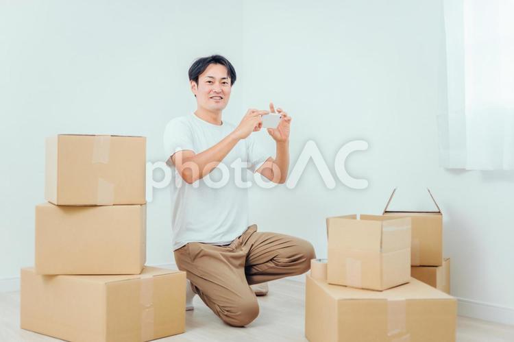 ダンボールとスマホを使う男性 引越し,スマホ,荷造りの写真素材