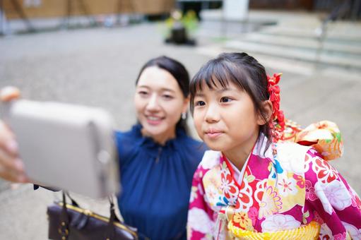 着物姿の娘と笑顔で写真を撮る母親 着物姿の娘と笑顔で写真を撮る母親 七五三,お参り,七五三参りの写真素材