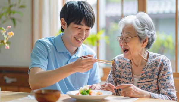 食事介助をする男性介護士と高齢女性 食事介助をする男性介護士と高齢女性の写真