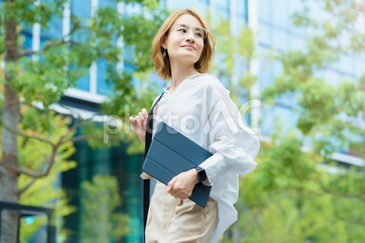 緑あふれるオフィス街を歩く女性  女性,フリーランス,自由の写真素材