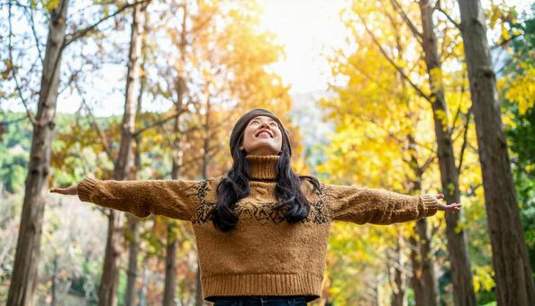 紅葉の中で深呼吸する秋服の日本人女性 紅葉の中で深呼吸する秋服の日本人女性の写真