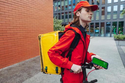 スマートフォンを使うフードデリバリーの男性 配達,フードデリバリー,デリバリーの写真素材