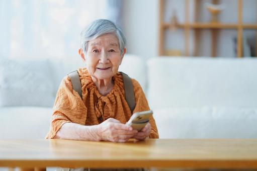 カメラ目線でスマホを持つ高齢女性 女性,スマートフォン,持つの写真素材