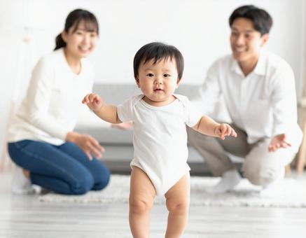 初めて歩いた赤ちゃんと見守る若い両親 初めて歩いた赤ちゃんと見守る若い両親の写真
