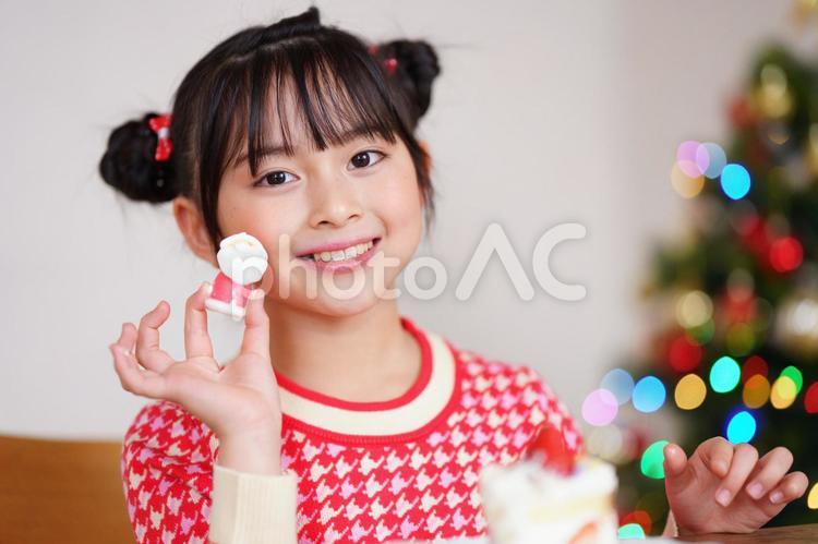 カメラ目線でサンタクロースのお菓子を持つ女の子 女の子,クリスマス,サンタクロースの写真素材