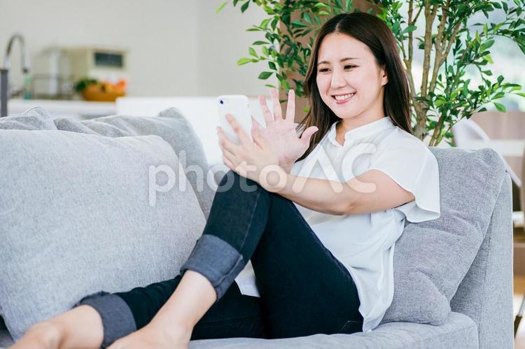 ソファでスマホを使う女性 スマホ,スマートフォン,女性の写真素材