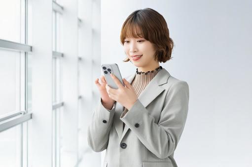 スマホを使う笑顔の女性・ビジネスウーマン 女性,スマホ,スマートフォンの写真素材