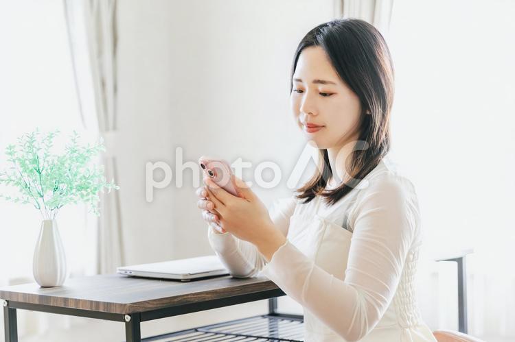 自宅でスマホを使う20代女性 スマホ,スマホ女性,スマートフォンの写真素材