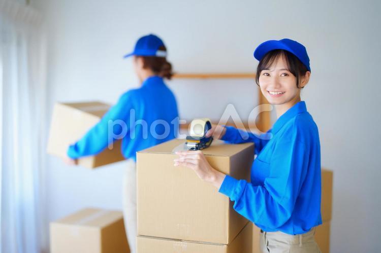 カメラ目線でテープを貼る引越し屋さん 女性,人物,若者の写真素材