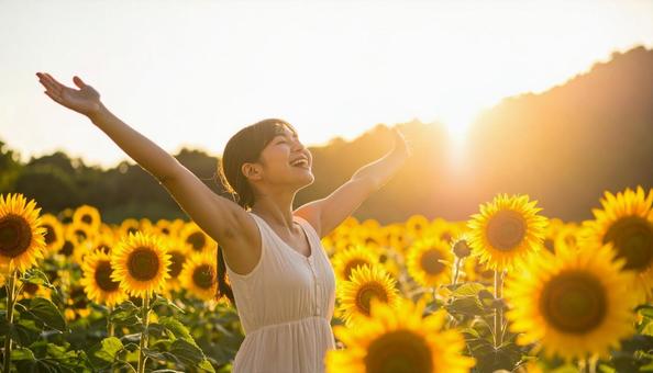 ひまわり畑で夏の陽射しを満喫する女性の写真