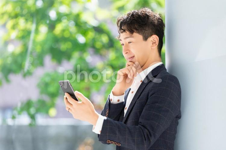 スマホの画面を見て考える男性ビジネスマン 男性,スマホ,ビジネスの写真素材