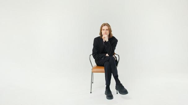 椅子に座りカメラ目線でポーズするスーツ男性 椅子に座りカメラ目線でポーズするスーツ男性の写真