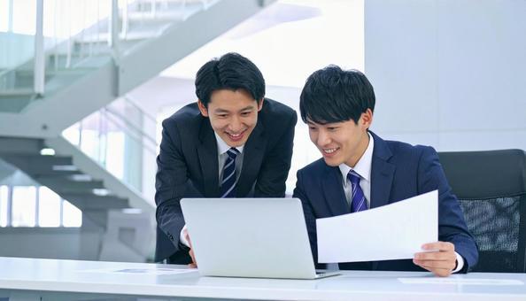 パソコンと資料を見ながら相談する社員の写真