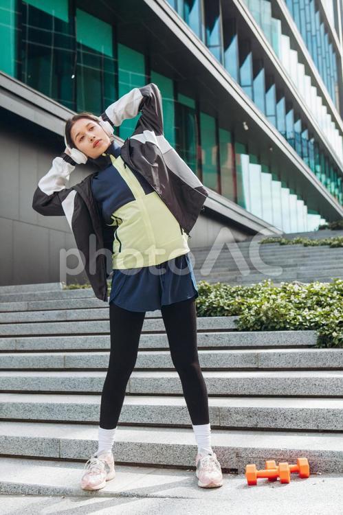 階段で腰をまげて準備運動する女性 女性,ヘッドフォン,人物の写真素材