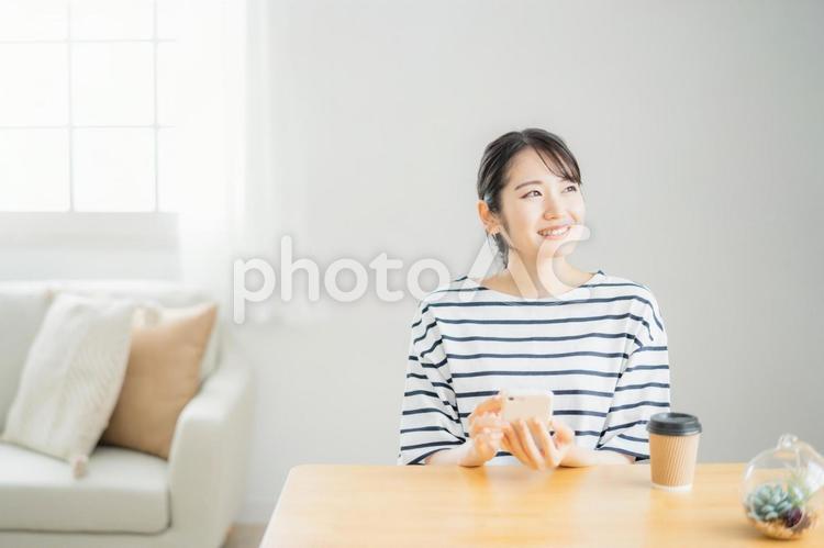 テーブルでスマホを使う女性（笑顔） スマホ,アプリ,女性の写真素材