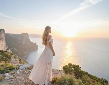 夕日を眺める女性 海と断崖 夕日を眺める女性 海と断崖の写真