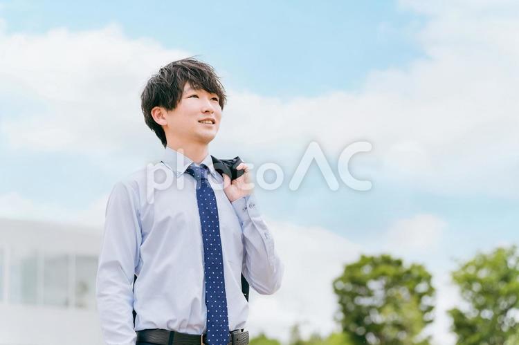 青空とオフィスの前に立つ若いビジネスマン ビジネスマン,男性,ビジネスの写真素材