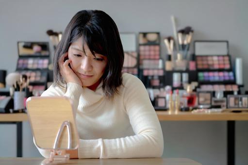 化粧道具と悩む女性 女性,鏡,メイクの写真素材