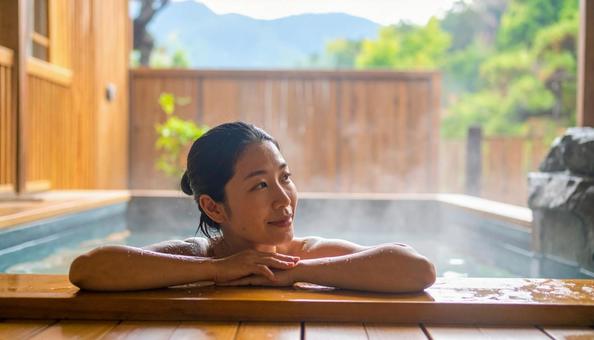 温泉につかってリラックスする若い女性 温泉につかってリラックスする若い女性の写真