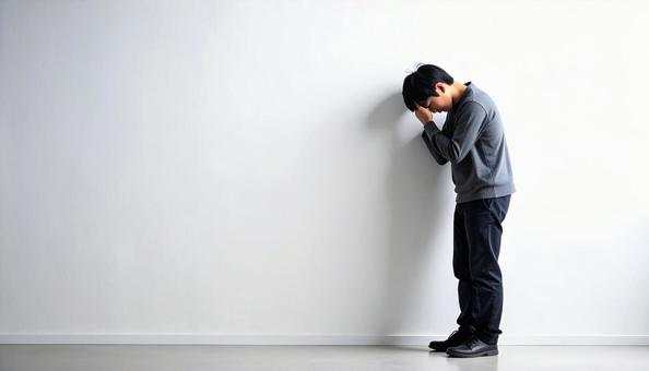壁に寄りかかる落ち込んでいる日本人男性 壁に寄りかかる落ち込んでいる日本人男性の写真