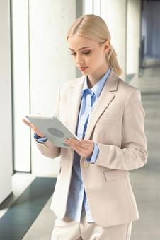 オフィスの通路でタブレットを使うビジネスウーマン ビジネスウーマン,ビジネス,女性の写真素材