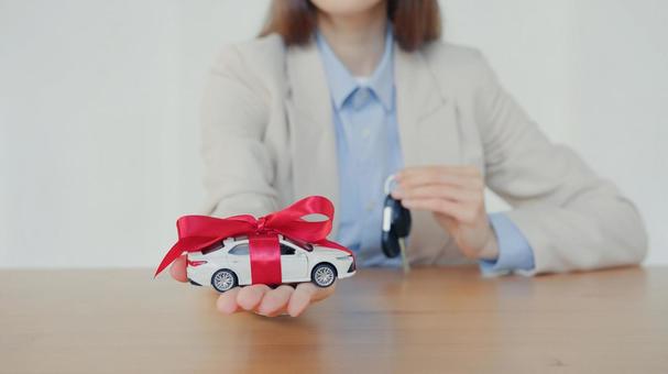 リボンを巻いた車の模型とストラップを持つ手元 保険業,事務職,接客業の写真素材
