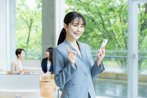 スマホを操作するビジネスウーマン スマホ,笑顔,ビジネスウーマンの写真素材