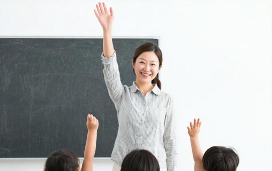 手を挙げて説明する女性教師 手を挙げて説明する女性教師の写真