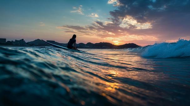 夕暮れの海で最後の波に乗るサーファー女性 夕暮れの海で最後の波に乗るサーファー女性の写真