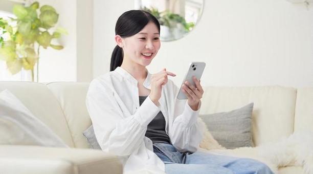 リビングでスマホを操作するアジア人女性 リビングでスマホを操作するアジア人女性 スマートフォン,操作,女性の写真素材