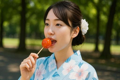 浴衣姿の女性がりんご飴を食べるシーン 浴衣姿の女性がりんご飴を食べるシーンの写真