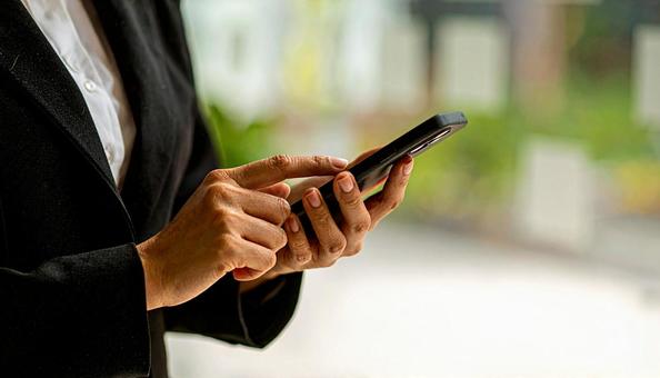 スマートフォンを操作する女性の手元 スマートフォンを操作する女性の手元の写真