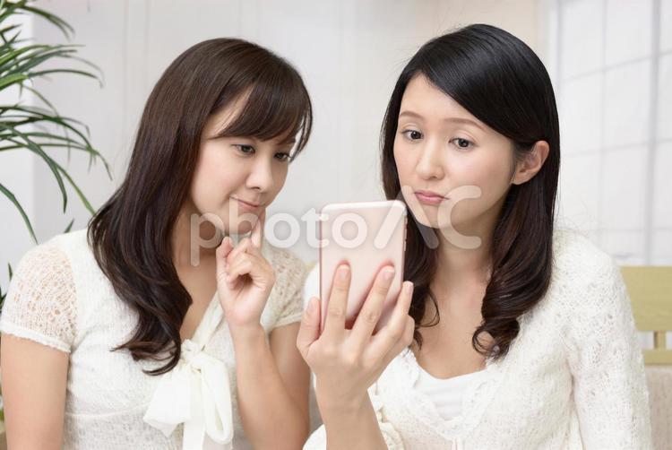 不安そうな表情の二人の女性 女性,女,スマートフォンの写真素材