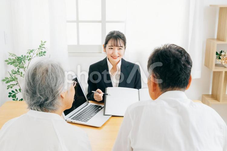 資料で説明するスーツ姿の女性と高齢者夫婦 相談,税理士,司法書士の写真素材