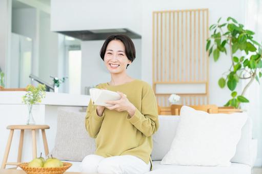 リビングで財布を持つミドルの女性 リビングで財布を持つミドルの女性の写真