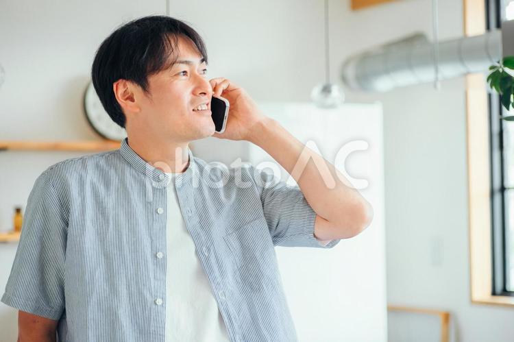家でスマホを使う男性（通話・笑顔） 電話,スマホ,男性の写真素材