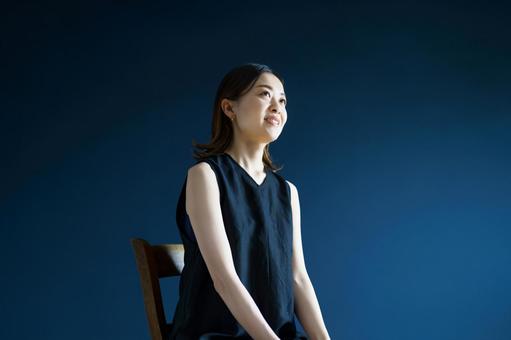 藍色の壁の部屋でリラックスした表情の女性  ポートレート,女性,黒髪の写真素材