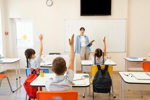 手を挙げる子どもたちの後ろ姿と先生 女性,女の子,男の子の写真素材