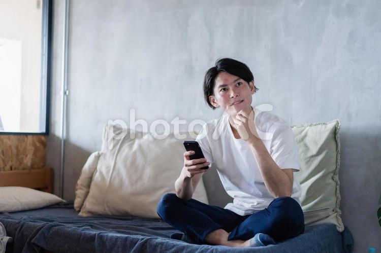 一人暮らしの家でスマホを使う若い男性 ストレス解消,スマホ,中国人の写真素材