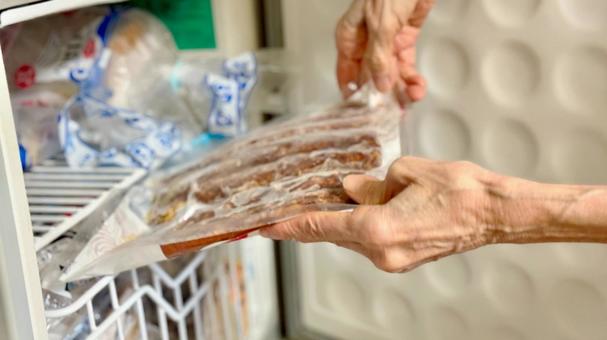 さんまの蒲焼きを冷凍庫に入れる高齢女性 さんまの蒲焼きを冷凍庫に入れる高齢女性 冷凍食品,パック,冷凍の写真素材