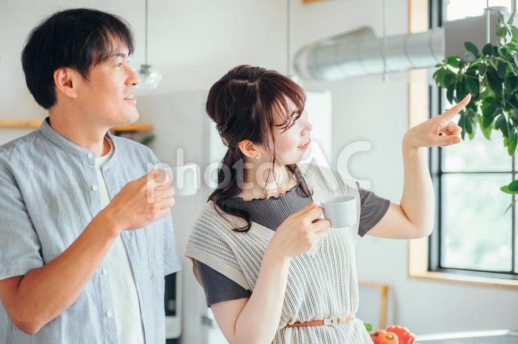 キッチンの前でコーヒーを飲む男女（夫婦） 夫婦,新婚,お茶の写真素材