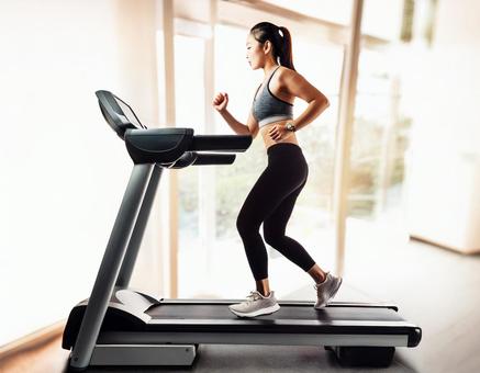 ランニングマシンでトレーニングする女性 ランニングマシンでトレーニングする女性の写真