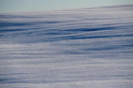 風と光が織りなす雪原の青い波紋の質感 雪原,丘陵,雪の写真素材