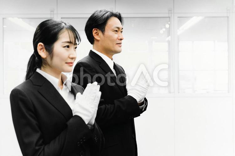 白手袋をつけて合掌するスーツ姿の男女 葬祭ディレクター,白手袋,礼服の写真素材