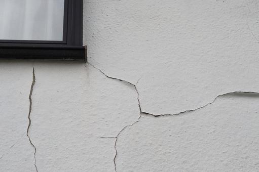 劣化してひび割れした白い外壁と窓枠 劣化してひび割れした白い外壁と窓枠の写真