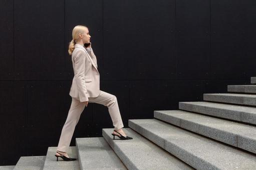 オフィスビルの外の階段を電話しながら登る女性 ビジネスウーマン,ビジネス,女性の写真素材